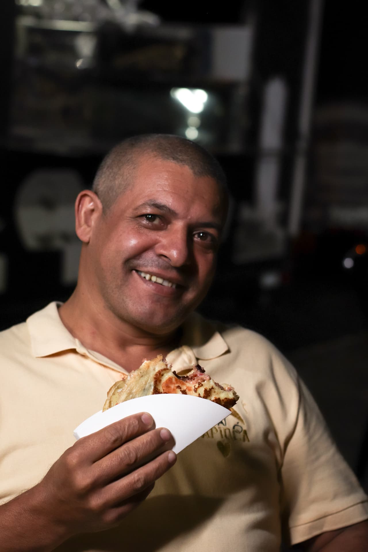 Cliente do Ó Paí Ó sorrindo com uma tapioca na mão