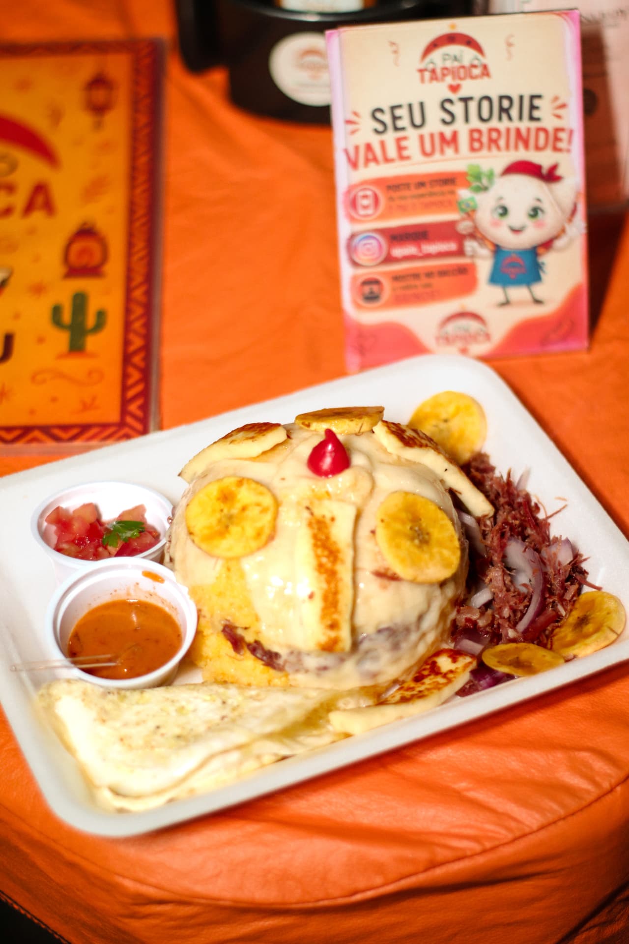 Bandeja de cuscuz recheado com banana-da-terra frita, carne-seca desfiada, ovo, vinagrete e molho de pimenta